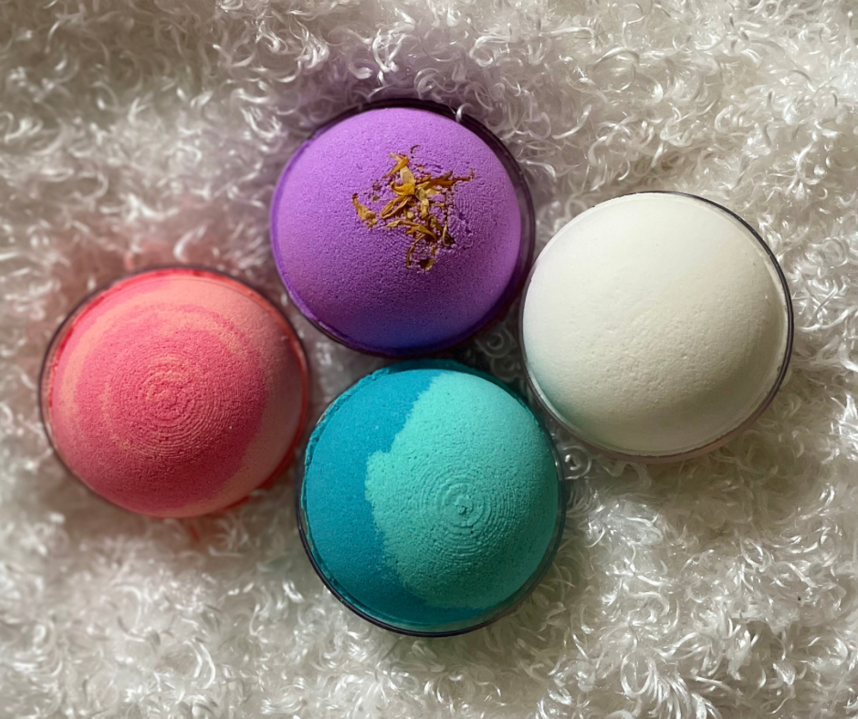 White, blue, purple, and pink bath bombs on fuzzy soft cloth.