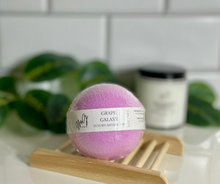 Load image into Gallery viewer, Round purple bath bomb with label on wooden soap tray.
