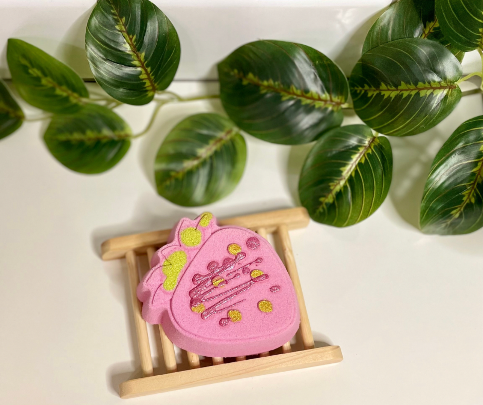 pink strawberry bath bomb on wooden tray