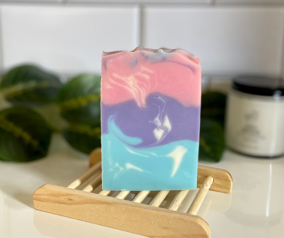 Pink, purple, blue layered swirled soap bar on wooden soap tray
