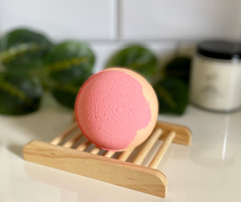 Orange and pink round bath bomb on wooden soap tray